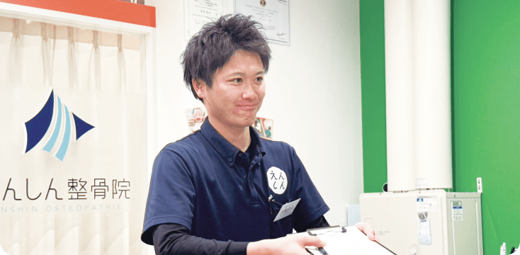 受付で問診票を差し出す男性スタッフの画像