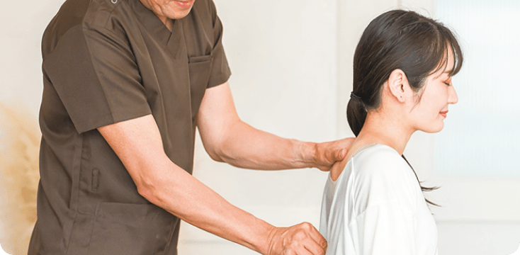 男性整体師が女性患者の背骨の状態を確認している様子