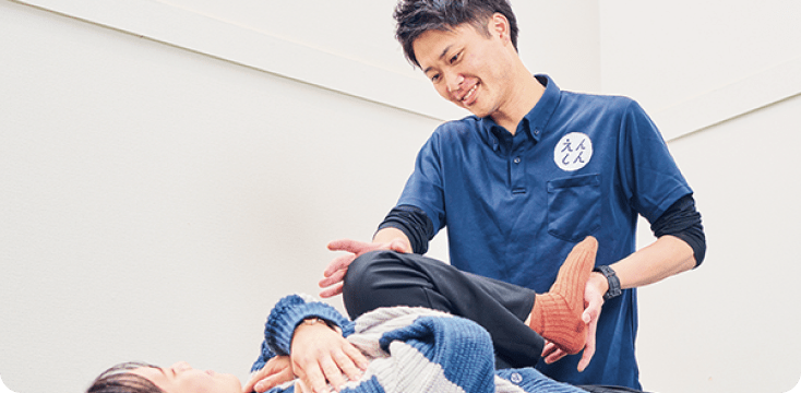 笑顔の男性整体師が女性患者に施術を行なっている様子