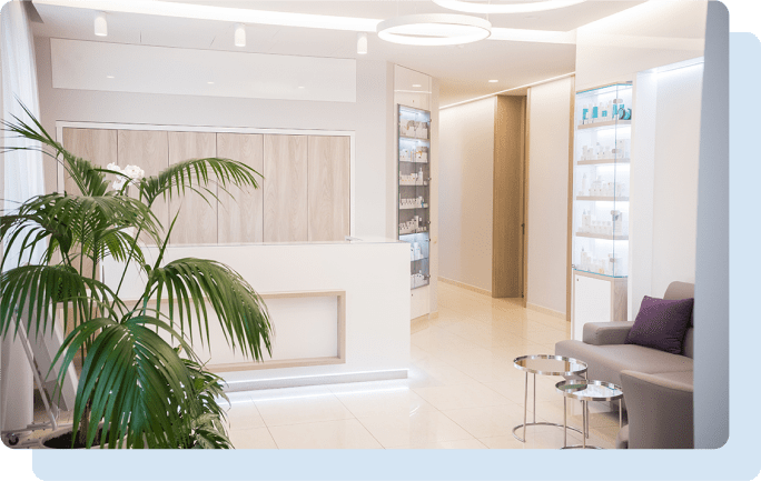 観葉植物やソファが置かれた、白を基調とした明るい受付ロビーのイメージ