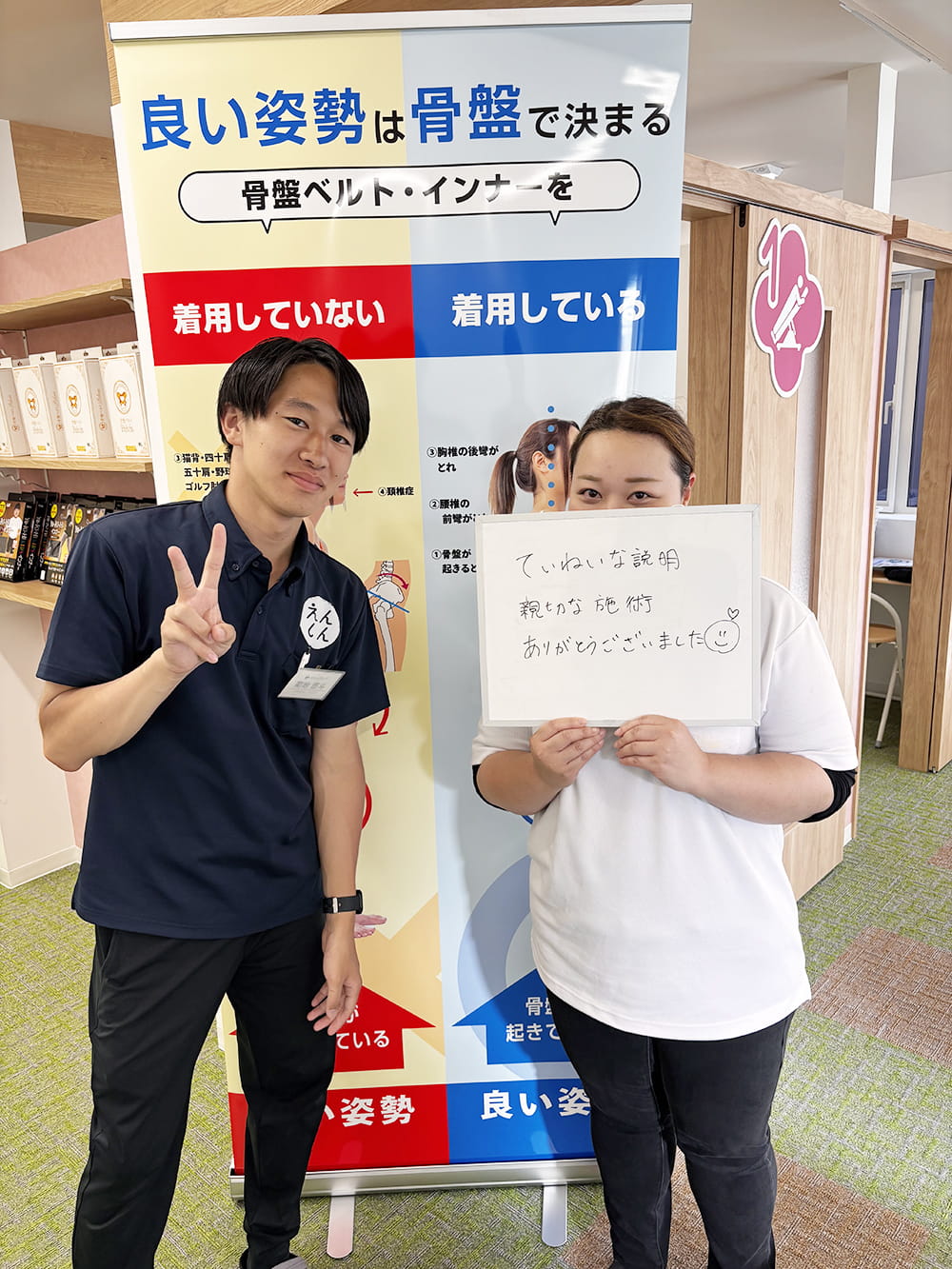 施術後の感想パネルを手にした患者が、制服姿のスタッフと笑顔で記念撮影している様子