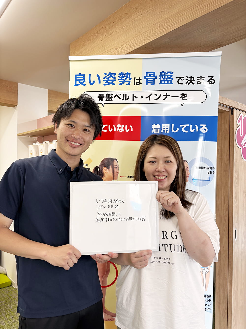 施術後の感想パネルを手にした患者が、制服姿のスタッフと笑顔で記念撮影している様子