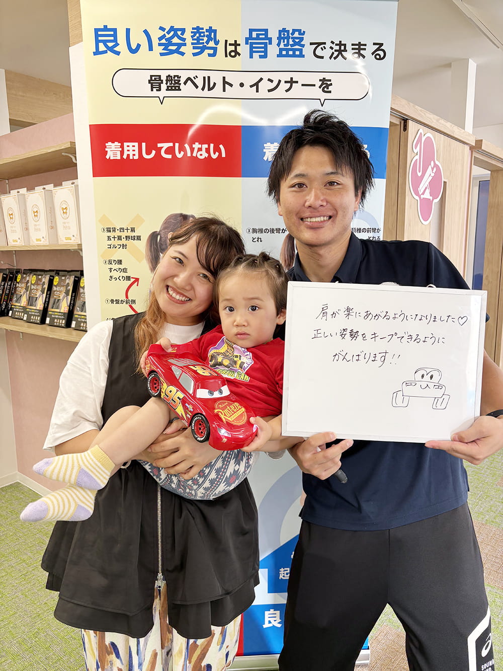 施術後の感想パネルを手にした患者が、制服姿のスタッフと笑顔で記念撮影している様子