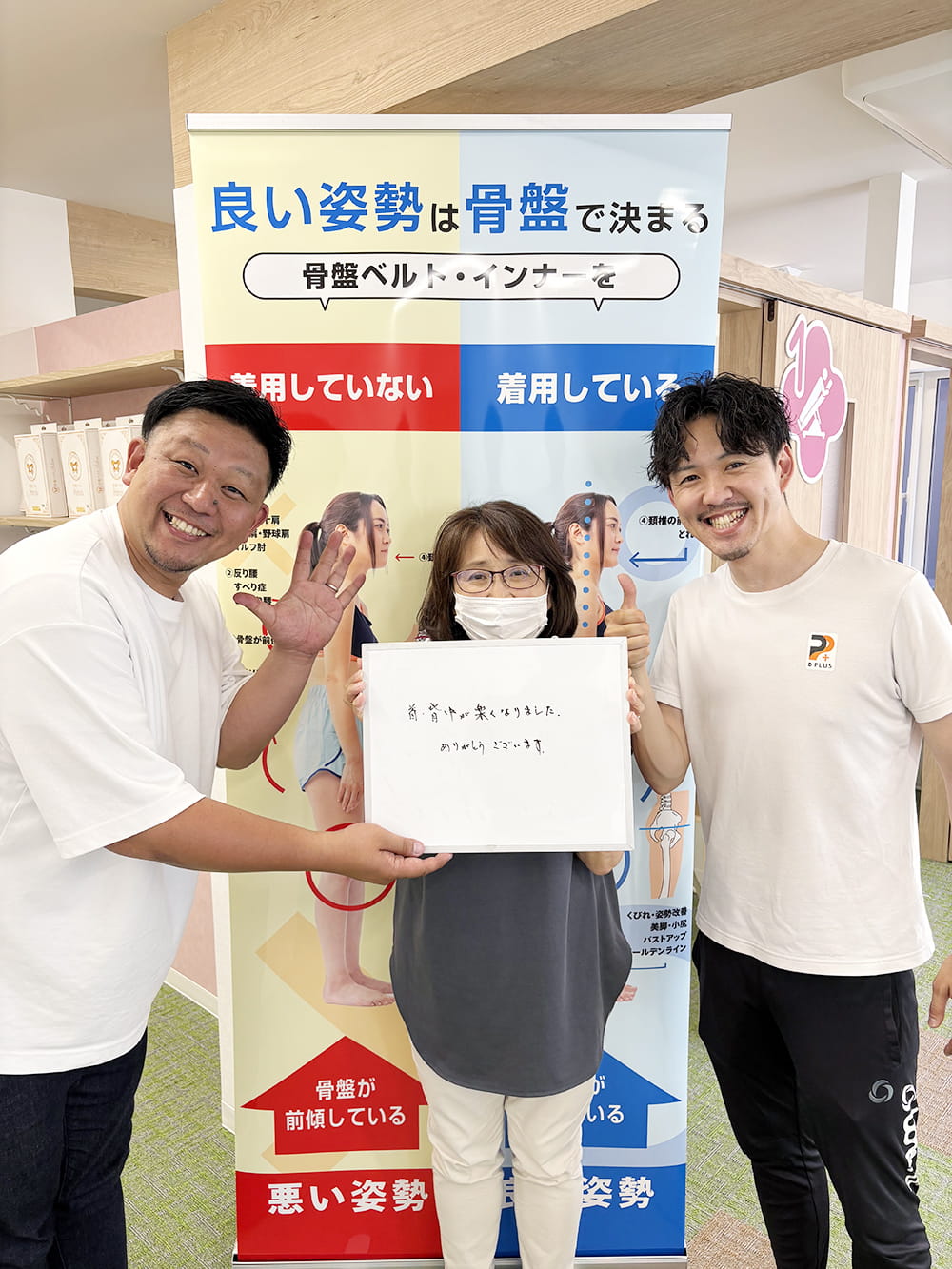 施術後の感想パネルを手にした患者が、制服姿のスタッフと笑顔で記念撮影している様子